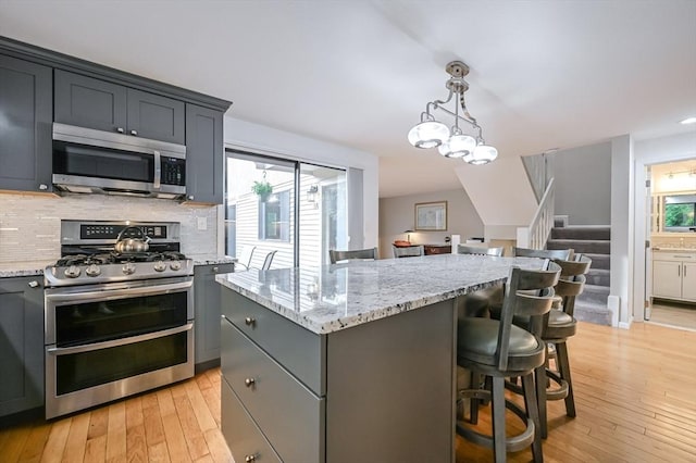 9 Country Club Ln Unit A, Milford, MA 01757 - kitchen with appliances with stainless steel finishes, gray cabinetry, light wood-style flooring, tasteful backsplash, and light stone counters