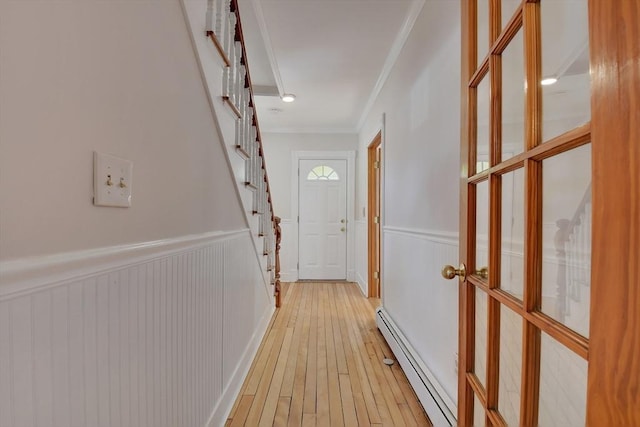 corridor featuring a baseboard heating unit, ornamental molding, and light hardwood / wood-style floors