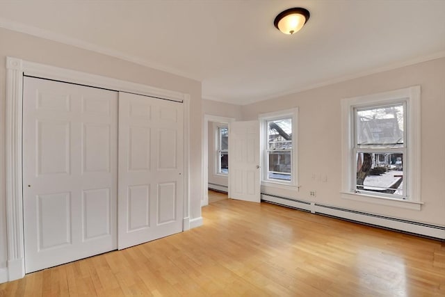 unfurnished bedroom with ornamental molding, light wood-type flooring, a closet, and a baseboard radiator