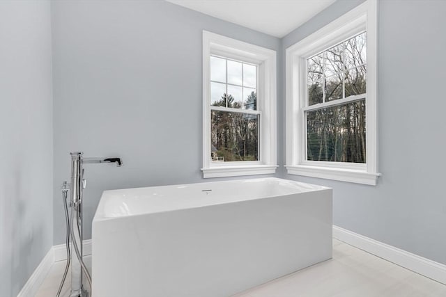 full bathroom with a freestanding tub and baseboards