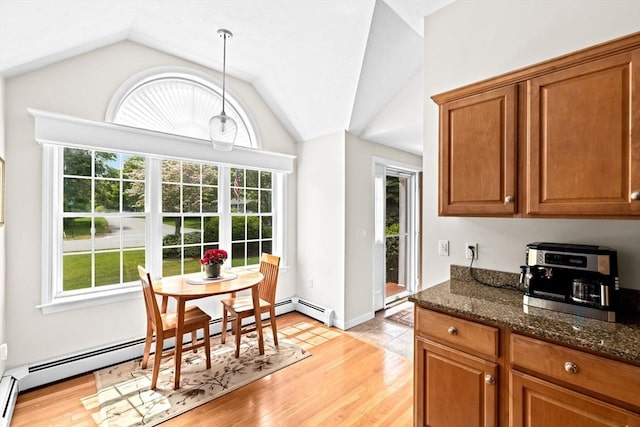 11 Quashnet Woods Dr, Mashpee, MA 02649 - kitchen with healthy amount of natural light, vaulted ceiling, brown cabinetry, dark stone counters, and a baseboard heating unit