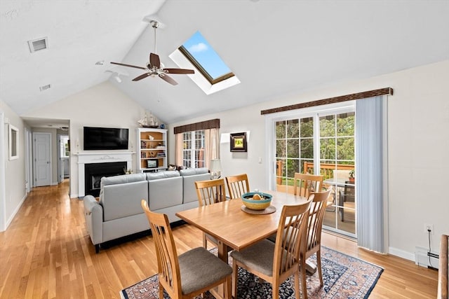 11 Quashnet Woods Dr, Mashpee, MA 02649 - dining area featuring a ceiling fan, light wood-type flooring, a skylight, a fireplace, and high vaulted ceiling