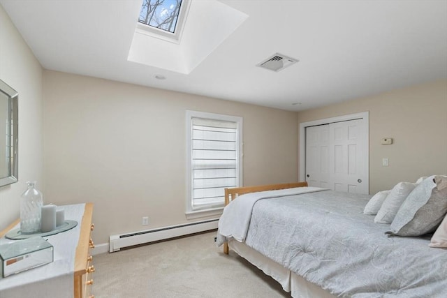 carpeted bedroom featuring a skylight, a closet, and a baseboard heating unit