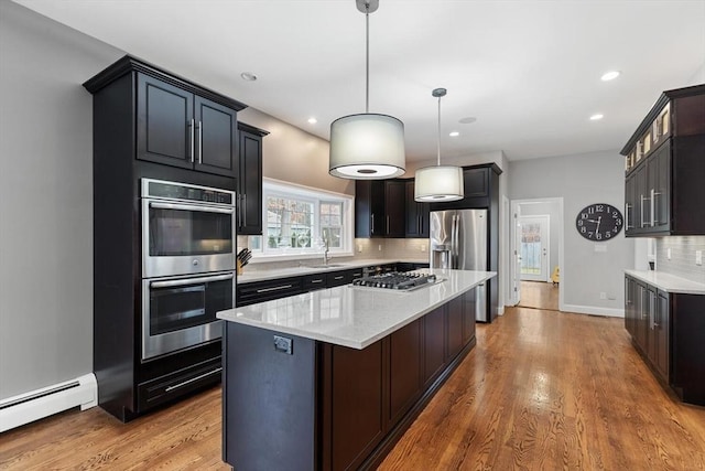 kitchen featuring sink, a center island, stainless steel appliances, hanging light fixtures, and baseboard heating