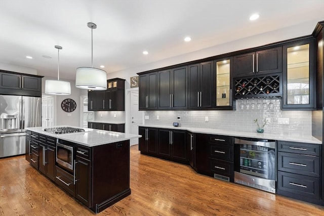 kitchen featuring stainless steel appliances, pendant lighting, a center island, light hardwood / wood-style floors, and wine cooler