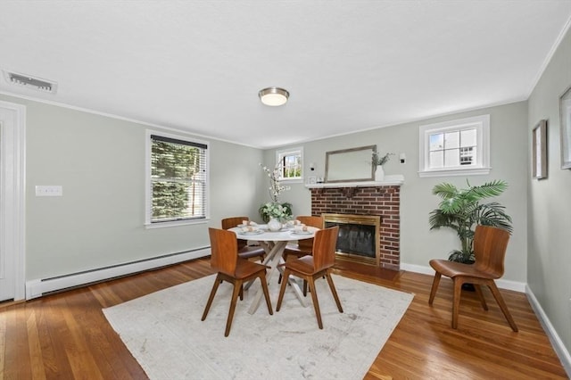 35 Crest Rd, Lynnfield, MA 01940 - dining space with a baseboard heating unit, wood finished floors, a brick fireplace, and ornamental molding