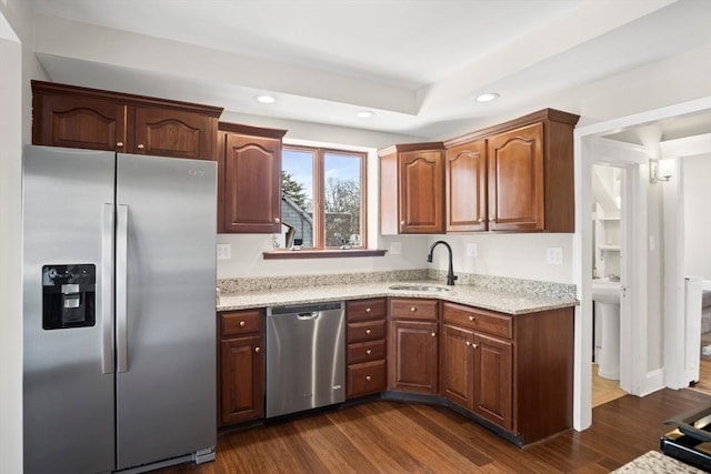 kitchen featuring light stone counters, sink, stainless steel appliances, and dark wood-type flooring