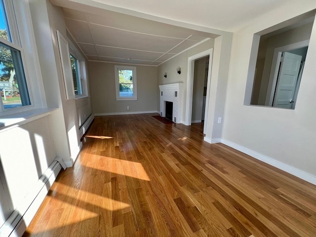 unfurnished living room featuring hardwood / wood-style floors, a fireplace, and a baseboard radiator