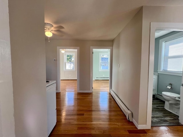 hallway featuring baseboard heating, dark hardwood / wood-style flooring, and plenty of natural light