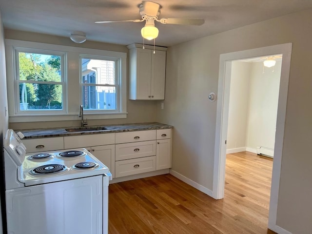 kitchen with white cabinets, light hardwood / wood-style flooring, a baseboard heating unit, and sink