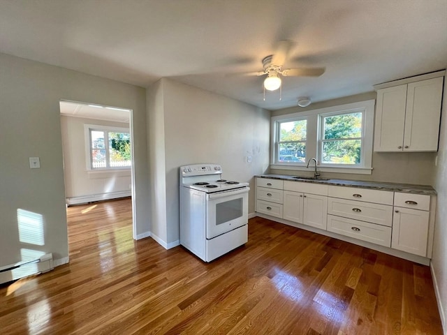 kitchen with sink, plenty of natural light, a baseboard heating unit, and electric stove