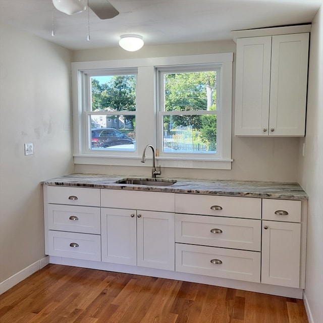 kitchen with white cabinetry, sink, and light hardwood / wood-style flooring