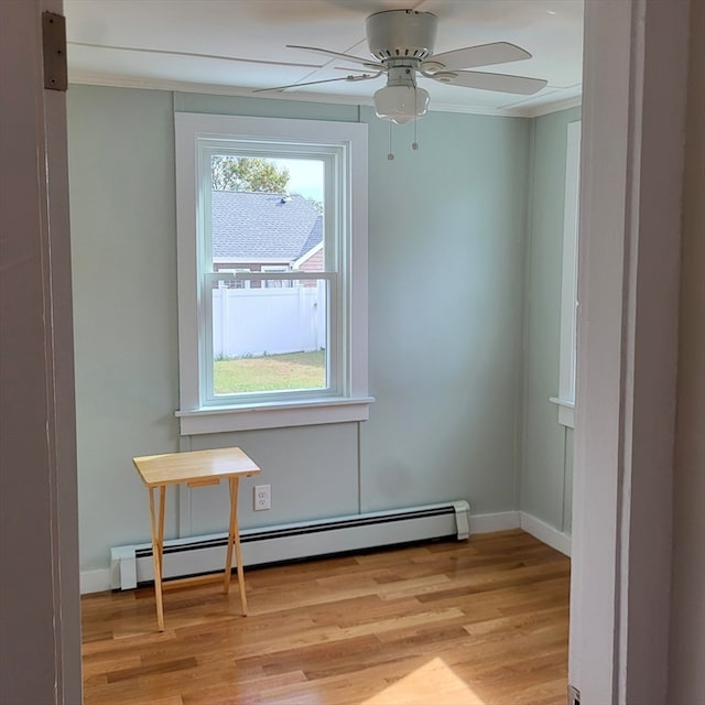 spare room with ceiling fan, crown molding, light wood-type flooring, and baseboard heating