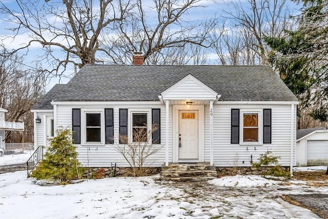 view of front of property with a shingled roof, an outbuilding, a chimney, and a garage