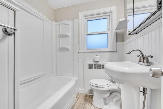 bathroom featuring a wealth of natural light, radiator heating unit, wood finished floors, and toilet