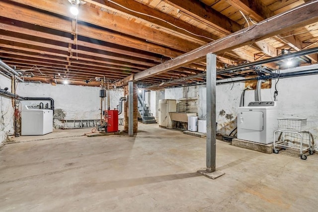 unfinished basement featuring a heating unit, stairway, a sink, and independent washer and dryer