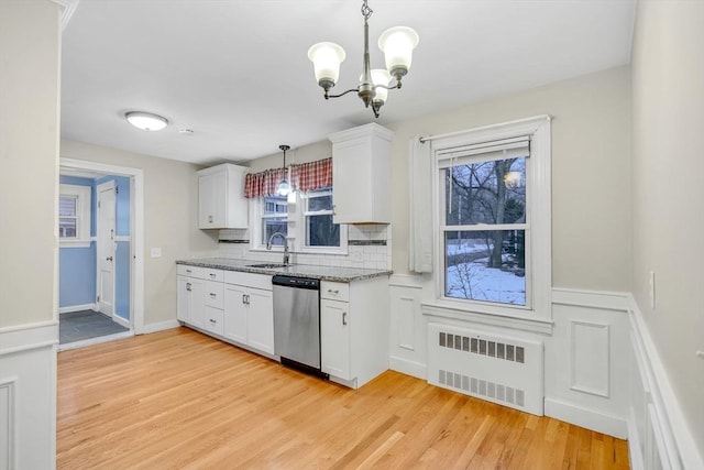 kitchen with light wood finished floors, radiator, white cabinetry, a sink, and dishwasher