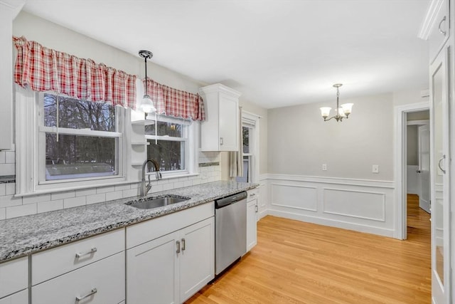 kitchen with decorative backsplash, light wood-style floors, white cabinets, a sink, and dishwasher