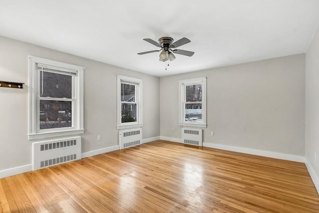 unfurnished room with hardwood / wood-style flooring, radiator heating unit, and baseboards