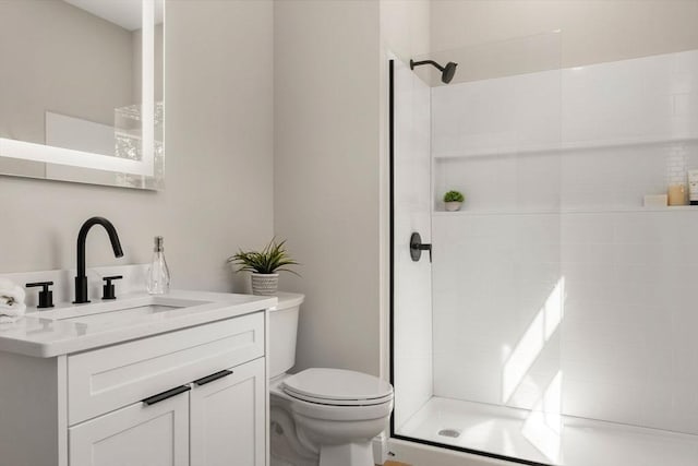 full bathroom with a tile shower, toilet, and vanity