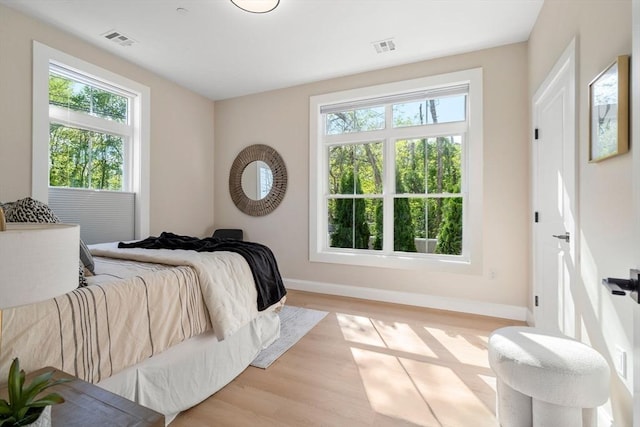 bedroom with multiple windows, baseboards, and light wood-type flooring