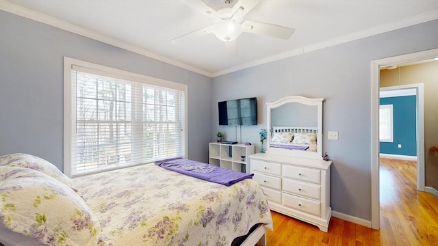 bedroom featuring crown molding, baseboards, light wood-style floors, and multiple windows