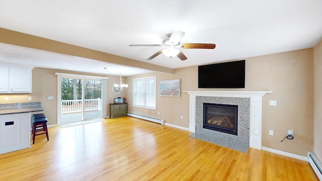 unfurnished living room with a baseboard radiator, ceiling fan with notable chandelier, a baseboard heating unit, light wood finished floors, and baseboards