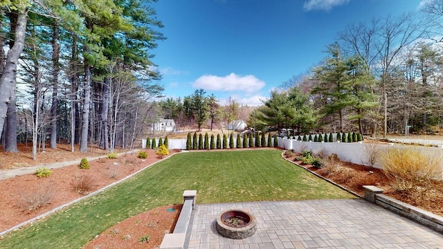 view of yard with fence, a fire pit, and a patio