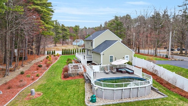 rear view of house featuring a wooden deck, a fenced backyard, a fenced in pool, and a yard