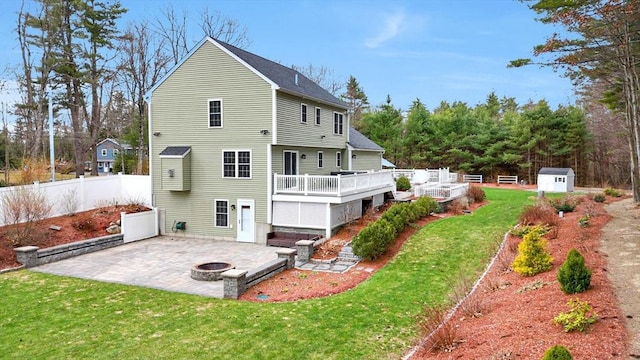 back of house featuring a lawn, a deck, a fire pit, fence, and a patio