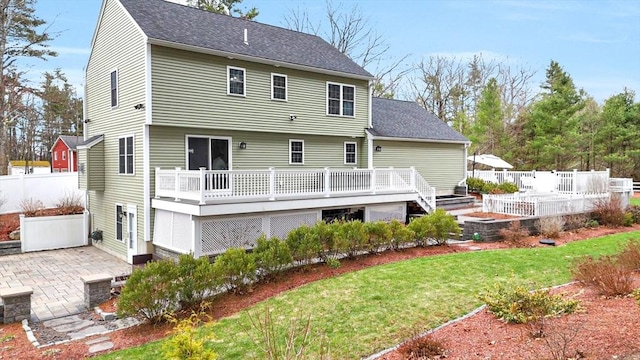 back of house with a lawn, roof with shingles, and a deck