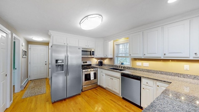 kitchen featuring white cabinets, baseboard heating, a sink, and appliances with stainless steel finishes