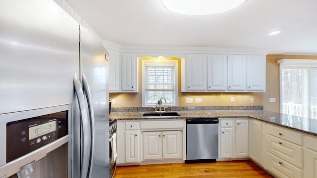 kitchen with plenty of natural light, stone counters, stainless steel appliances, and a sink