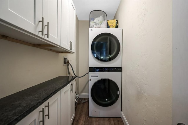 clothes washing area featuring cabinets, dark hardwood / wood-style flooring, and stacked washer and dryer