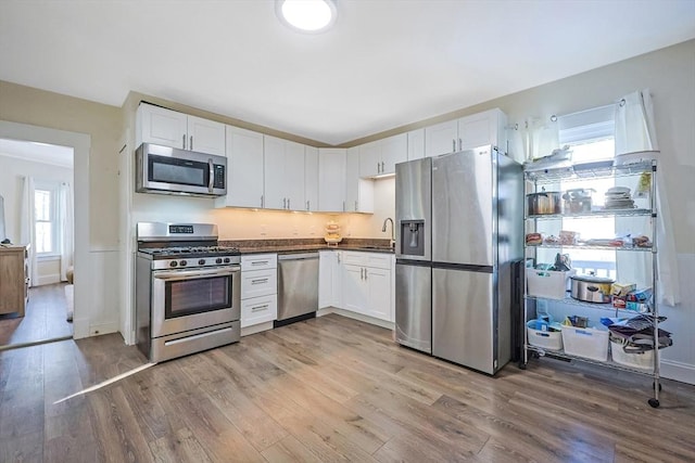 kitchen featuring white cabinets, hardwood / wood-style flooring, appliances with stainless steel finishes, and sink