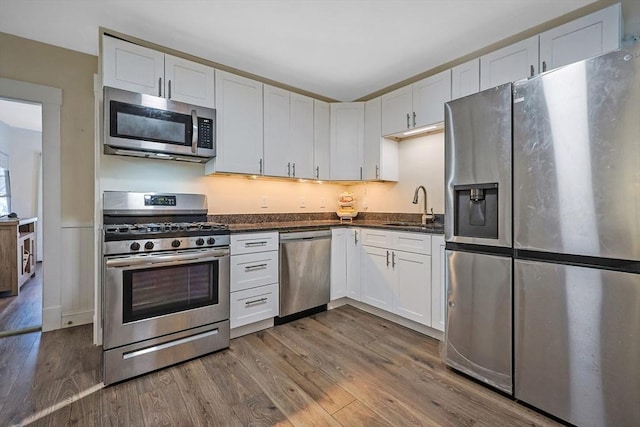 kitchen featuring white cabinetry, dark stone counters, sink, dark wood-type flooring, and stainless steel appliances