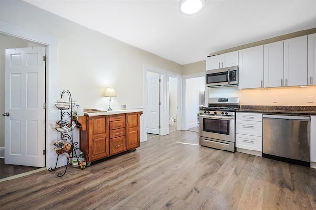 kitchen with white cabinets, light hardwood / wood-style flooring, and appliances with stainless steel finishes