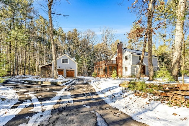 view of front of house with a balcony, a garage, a chimney, and an outdoor structure