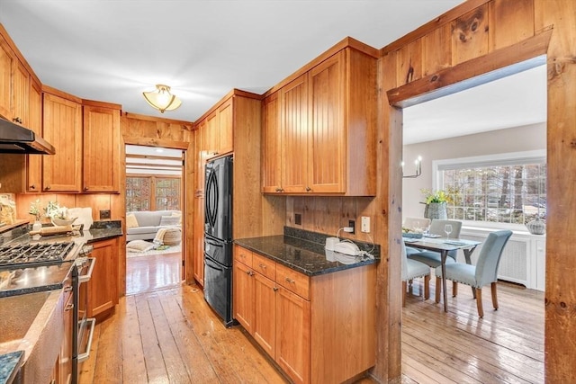 kitchen with light wood finished floors, stainless steel range with gas cooktop, freestanding refrigerator, and a healthy amount of sunlight