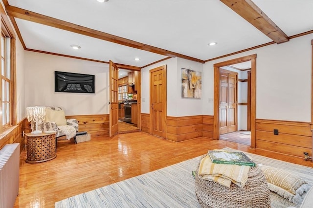 living area featuring wainscoting, radiator heating unit, ornamental molding, wood finished floors, and beam ceiling