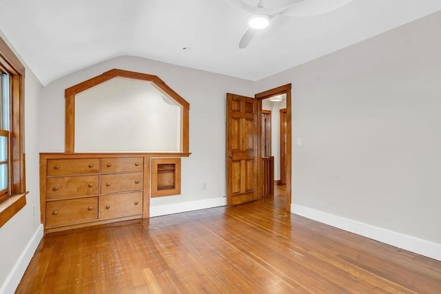 unfurnished bedroom with lofted ceiling, wood-type flooring, ceiling fan, and baseboards