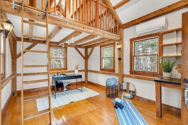 exercise area featuring a wall unit AC, plenty of natural light, wood-type flooring, and baseboards