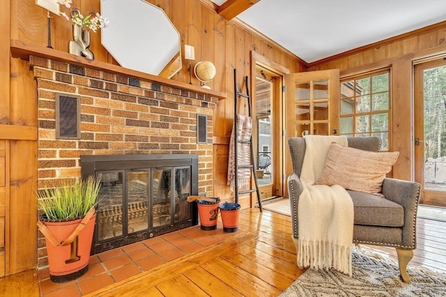 sitting room featuring visible vents, wood-type flooring, crown molding, wood walls, and a fireplace