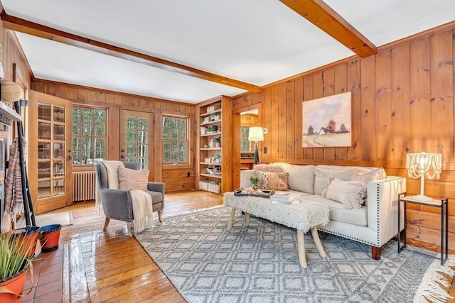 living room with wood-type flooring, beamed ceiling, wooden walls, and radiator heating unit