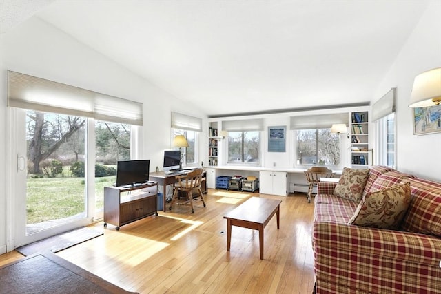 living area with a baseboard heating unit, a healthy amount of sunlight, and light wood-type flooring