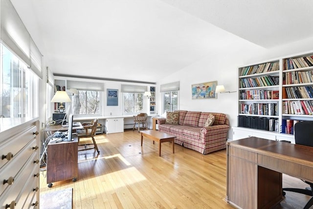 living area with baseboard heating, lofted ceiling, and hardwood / wood-style floors