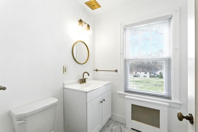 half bath with toilet, marble finish floor, and vanity