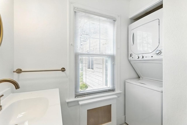 laundry room with laundry area, a sink, and stacked washer and clothes dryer