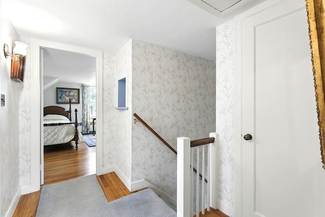 staircase featuring wallpapered walls and wood finished floors