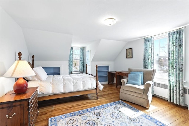 bedroom featuring lofted ceiling, wood finished floors, and radiator heating unit